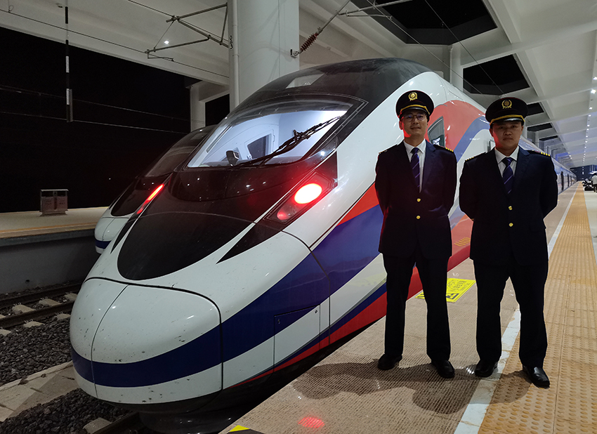 劉銀能（右一）與中國(guó)師父鄔俊鴻在動(dòng)車組前合影。受訪者供圖
